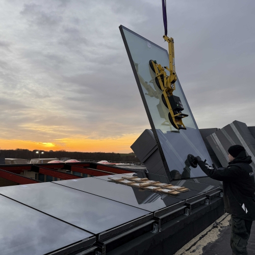 Montering af vinduer i Kolding – kranløft af stort glasparti til erhvervsbyggeri i solopgang
