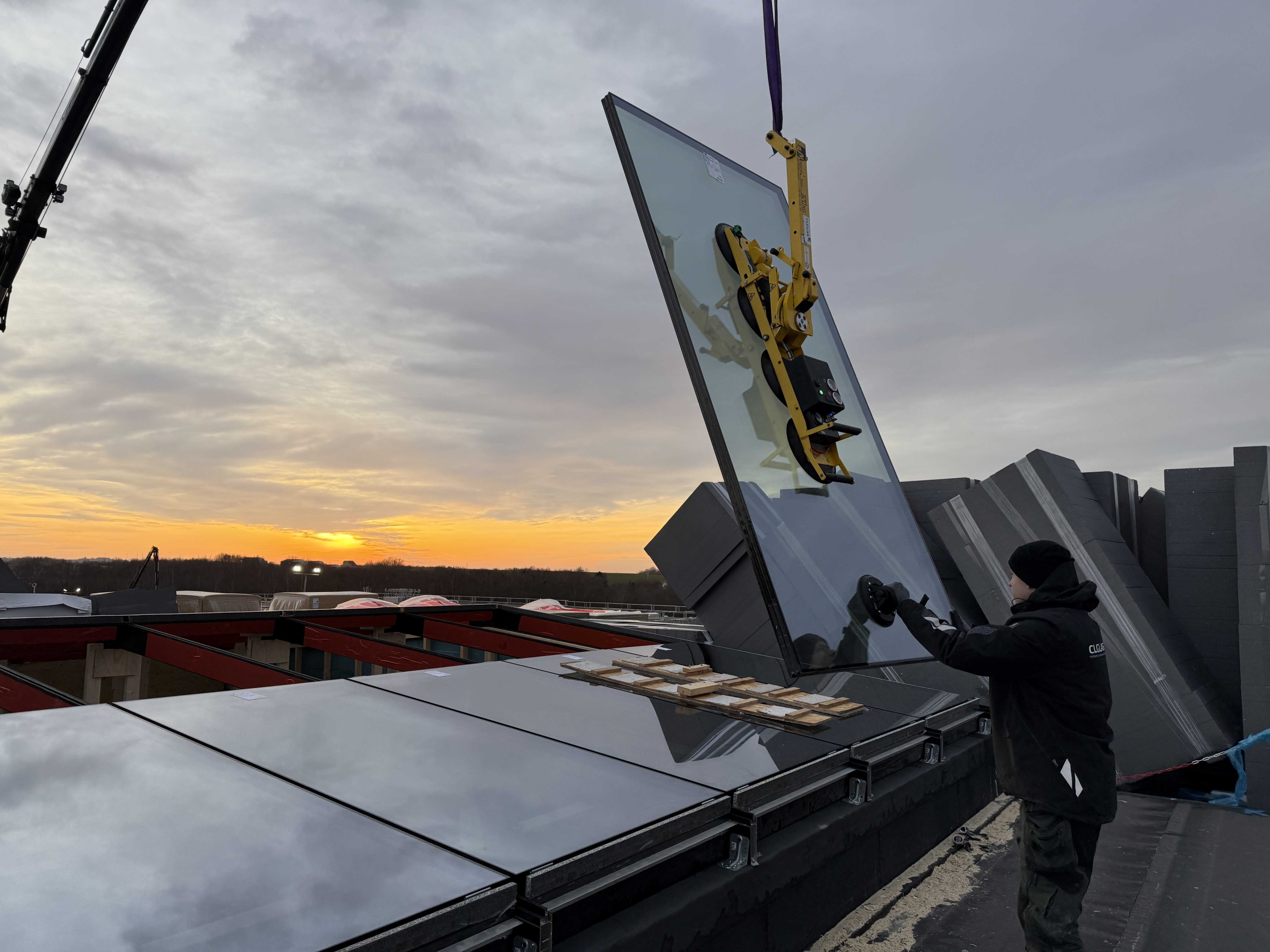 Montering af vinduer i Kolding – kranløft af stort glasparti til erhvervsbyggeri i solopgang