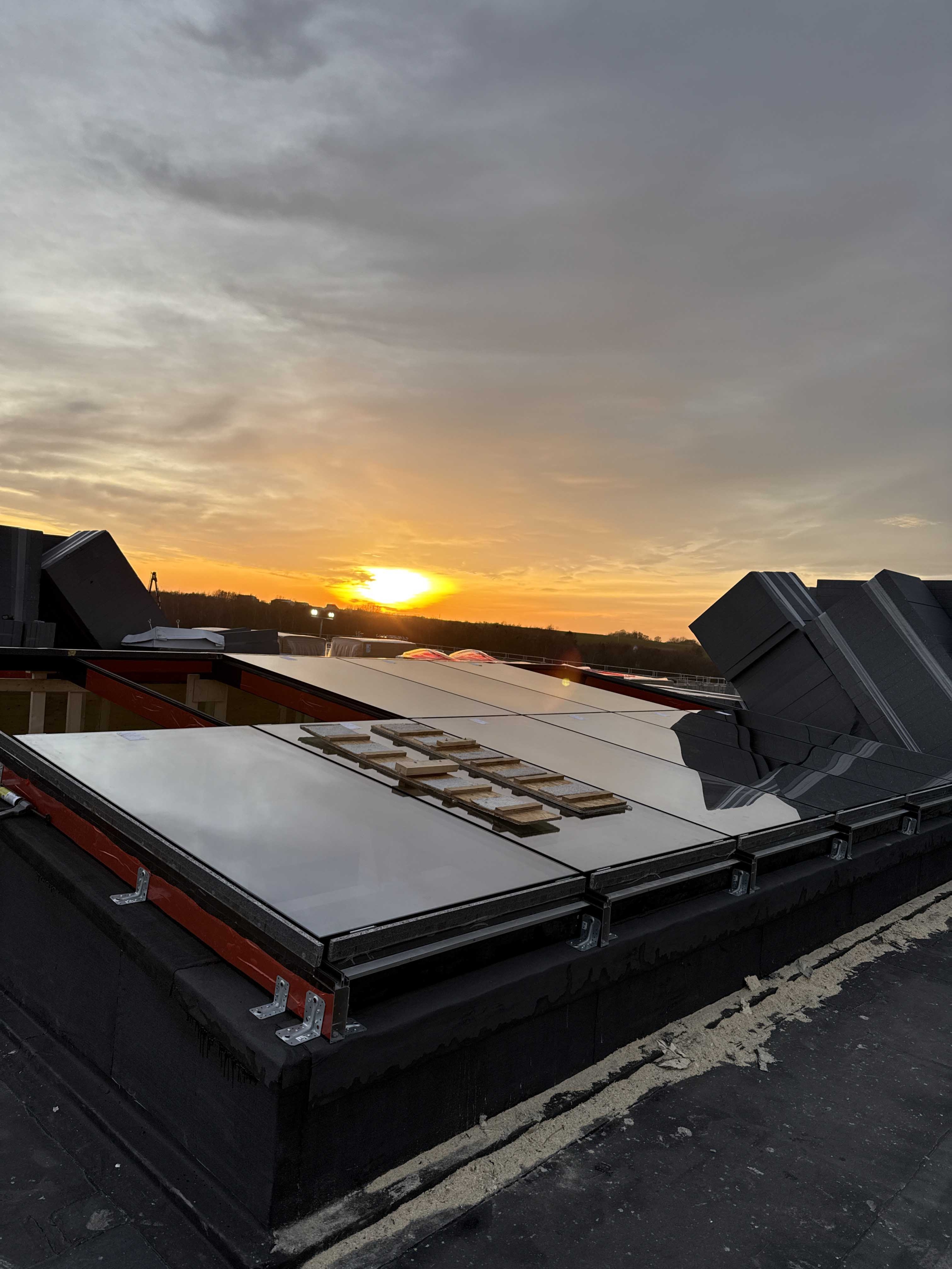 Færdigmonterede ovenlysvinduer i tagprojekt i Kolding – skinnende glas og solnedgang skaber et flot udtryk